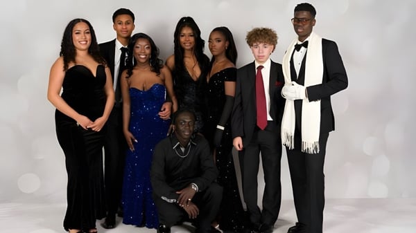 Eine Gruppe von Personen in formeller Kleidung steht vor einem weißen Hintergrund auf dem Campus des Sevenoaks Senior College.