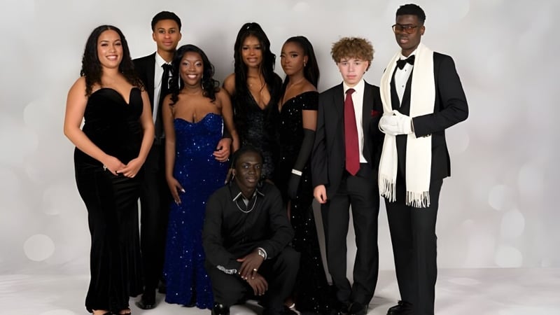 Eine Gruppe von Personen in formeller Kleidung steht vor einem weißen Hintergrund auf dem Campus des Sevenoaks Senior College.