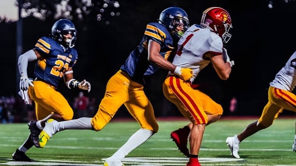 Zwei Footballspieler auf dem Feld bei Shady Side Academy während eines Spiels in der Dämmerung.