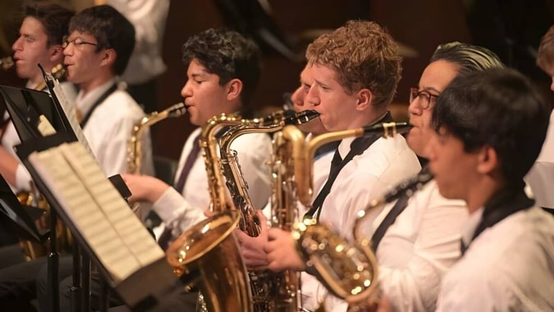 Eine Gruppe von Musikschülern der Shady Side Academy spielt auf einer Bühne in formeller Kleidung Blasinstrumente.