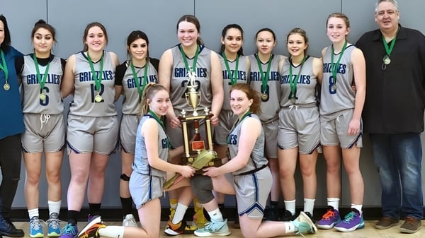 Schülerinnen der Shas Ti Kelly Road Secondary School posieren mit einem Pokal in der Sporthalle.