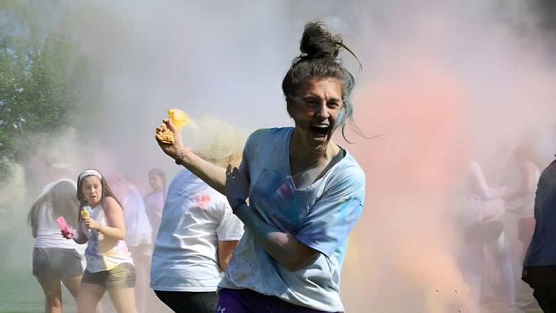 Eine Person ist auf dem Campus der Shattuck-St. Mary's School mit farbigem Pulver bedeckt und von weiteren Personen umgeben.