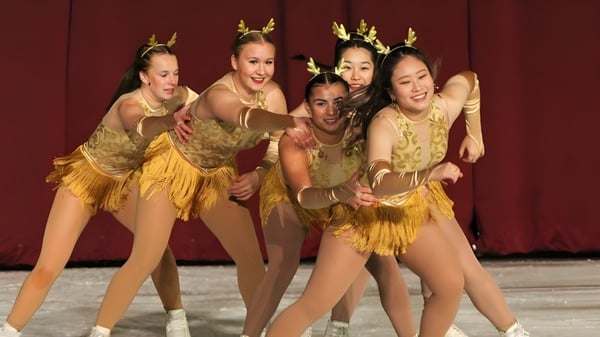 Fuenf Schuelerinnen der Shattuck-St. Marys School treten in goldenen Kostuemen vor rotem Vorhang auf einer Buehne auf.