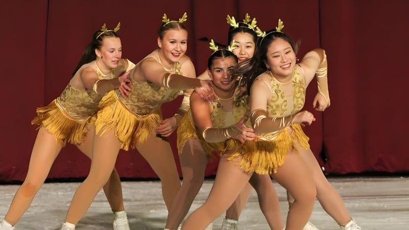 Fuenf Schuelerinnen der Shattuck-St. Marys School treten in goldenen Kostuemen vor rotem Vorhang auf einer Buehne auf.