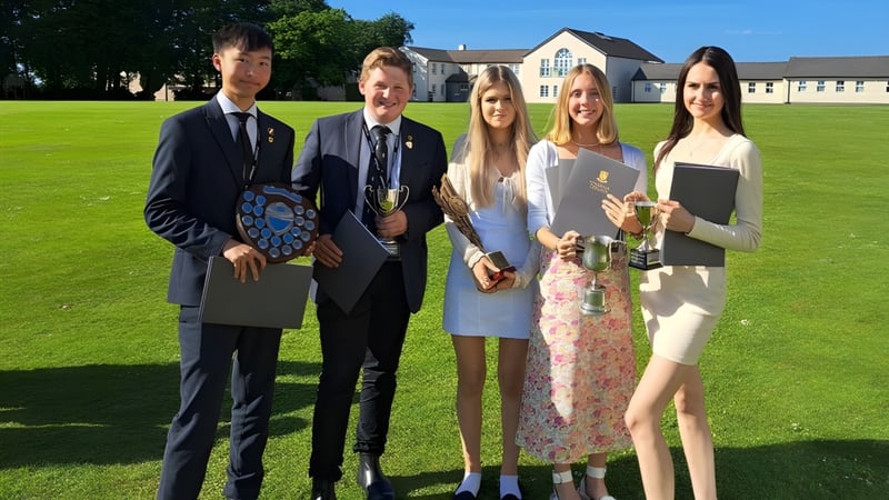 Eine Gruppe von fünf Personen steht auf einem Rasen vor dem Hauptgebäude des Shebbear College.