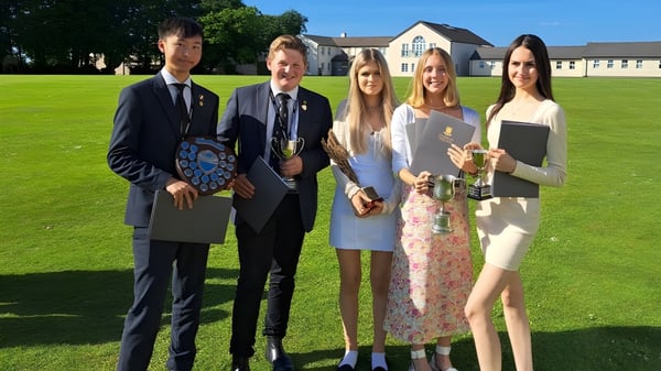 Eine Gruppe von fünf Studierenden steht auf einer Wiese vor dem Gebäude des Shebbear College.