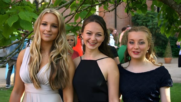 Drei Schülerinnen der Sherborne Girls' School stehen zusammen in einem Garten mit üppigem Grün und Bäumen.