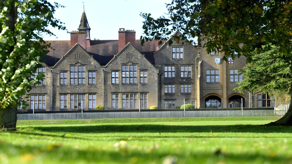 Das historische Hauptgebäude der Sherborne Girls' School mit hohem Turm und gepflegtem Grün rundherum.
