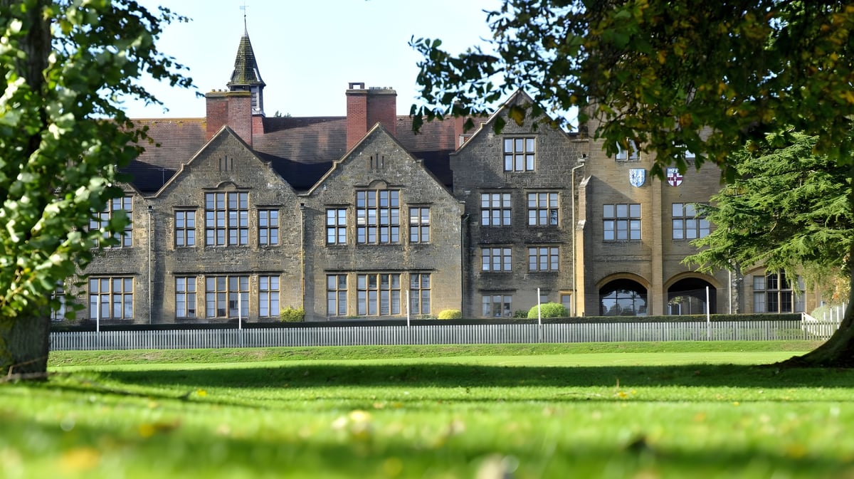 Das historische Hauptgebäude der Sherborne Girls' School mit hohem Turm und gepflegtem Grün rundherum.