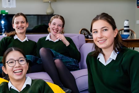 Vier Schülerinnen der Sherborne Girls' School sitzen gemeinsam auf einer Couch in einem Wohnzimmer.