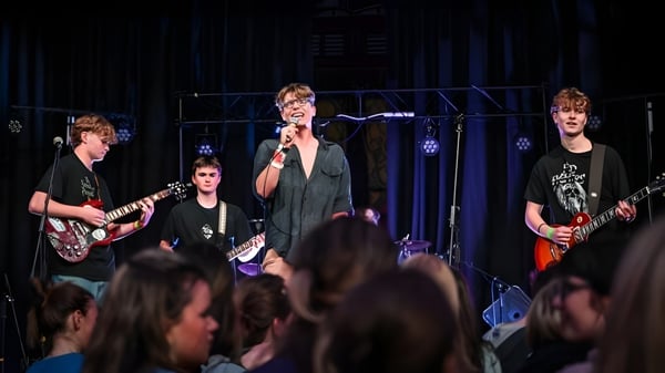 Eine Rockband der Sherborne School spielt auf der Bühne vor einem begeisterten Publikum.