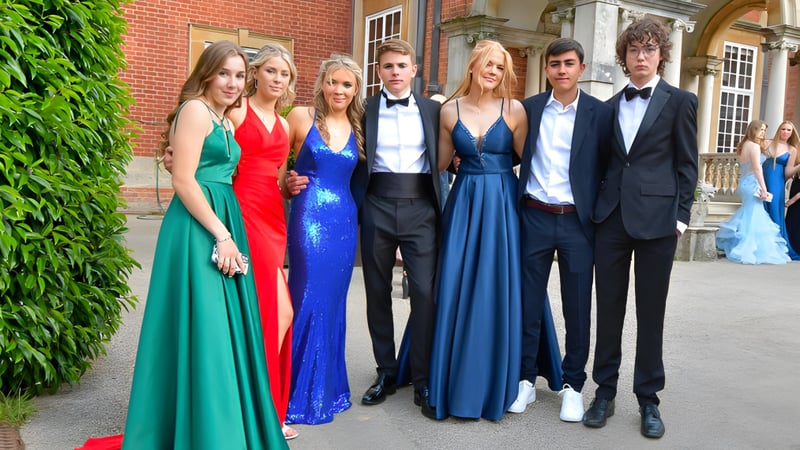 Eine Gruppe elegant gekleideter Personen steht vor dem Backsteingebäude der Sherfield School mit grüner Kulisse.
