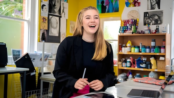 Eine Schülerin der Sherfield School sitzt lachend in einem Kunststudio umgeben von Kunstmaterialien.