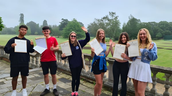 Eine Gruppe von Schülerinnen und Schülern der Sherfield School zeigt stolz ihre Zertifikate im Freien vor Bäumen und einem Zaun.