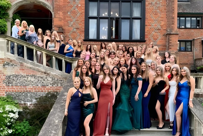 Eine Gruppe junger Frauen im formellen Kleid steht vor einem historischen Backsteingebäude auf dem Campus des Shiplake College.