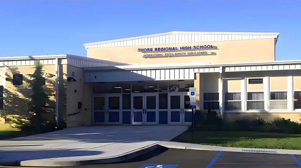 Das moderne Gebäude der Shore Regional High School mit dem Hauptzugang vor klarem blauem Himmel.