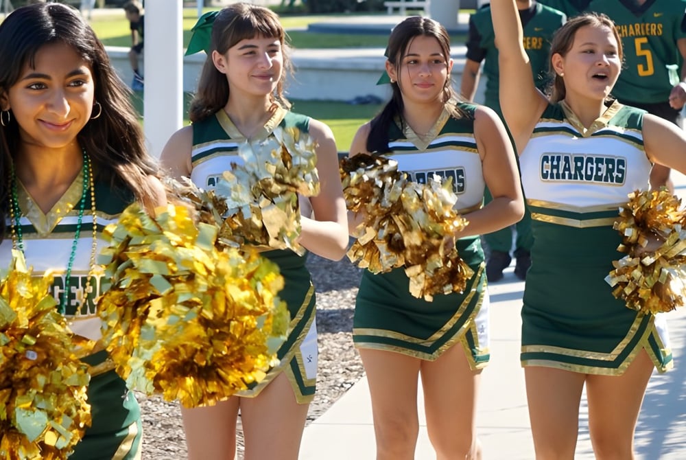 Eine Gruppe von Cheerleadern der Shorecrest Preparatory School führt eine Performance auf dem Sportfeld mit Stadion im Hintergrund durch.