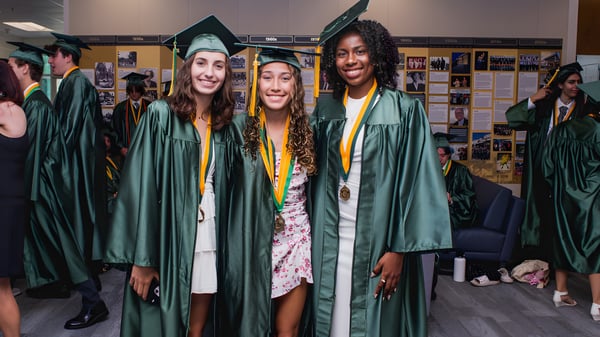 Eine Gruppe von Absolventinnen und Absolventen der Shorecrest Preparatory School steht im Flur der Schule in grünen Talaren und Hüten zusammen.