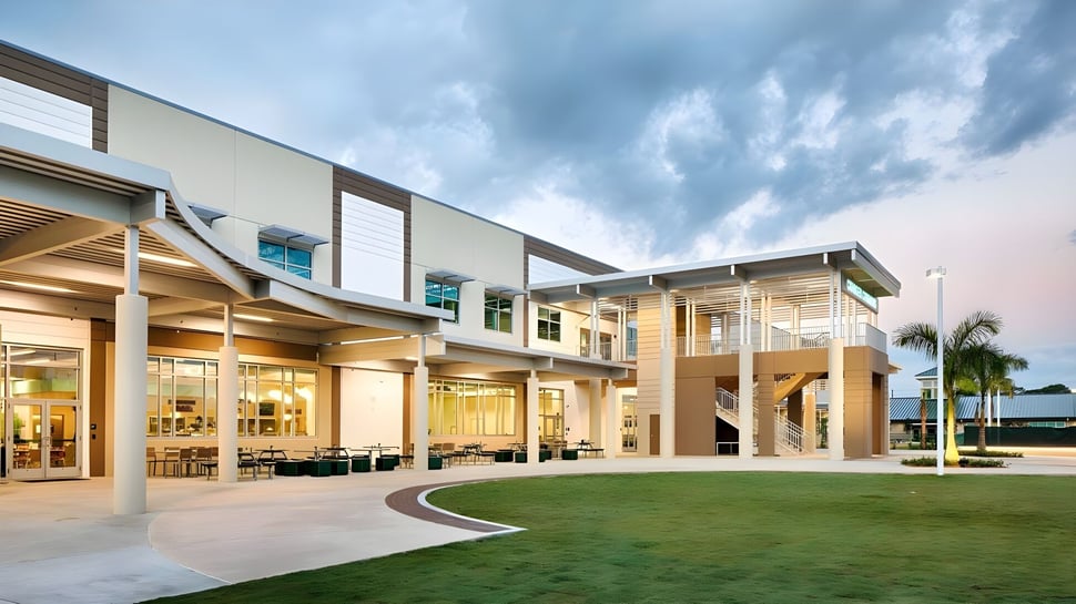 Das moderne mehrstöckige Gebäude der Shorecrest Preparatory School mit Glasfassade und einem grünen Innenhof bei bewölktem Himmel.