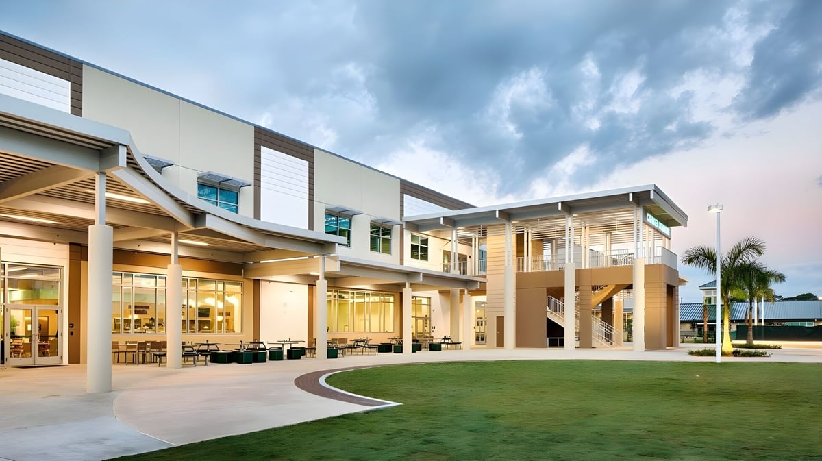 Das moderne mehrstöckige Gebäude der Shorecrest Preparatory School mit Glasfassade und einem grünen Innenhof bei bewölktem Himmel.