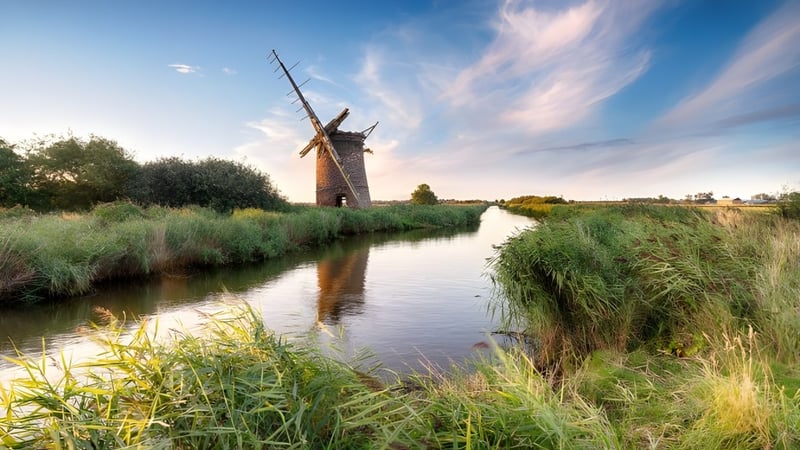 Eine malerische Windmühle steht neben einem ruhigen Kanal auf dem Gelände der Shrewsbury School.