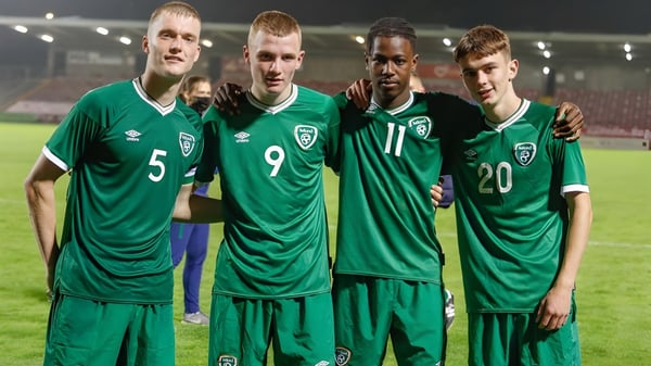 Vier Fußballspieler in grünen Trikots stehen auf dem Spielfeld der Sibford School unter Stadionlichtern.