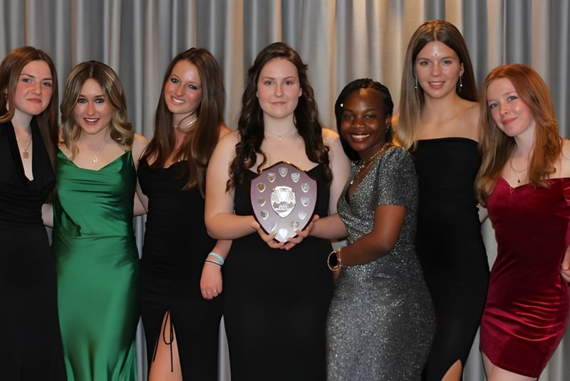 Eine Gruppe Frauen in formeller Kleidung posiert vor einem grauen Vorhang auf dem Campus der Sibford School.