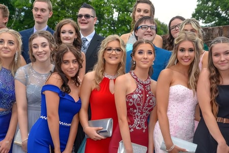 Eine Gruppe junger Menschen in formeller Kleidung posiert draußen vor Bäumen auf dem Gelände der Sidcot School.