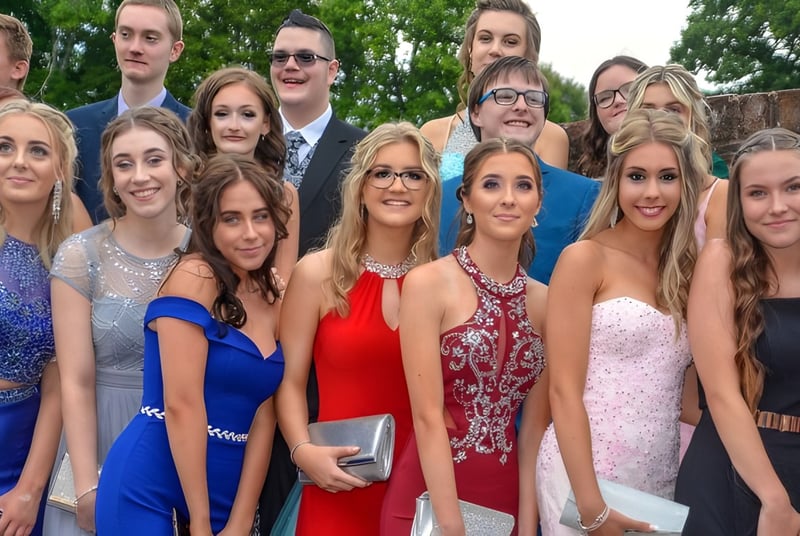 Eine Gruppe junger Menschen in formeller Kleidung posiert draußen vor Bäumen auf dem Gelände der Sidcot School.