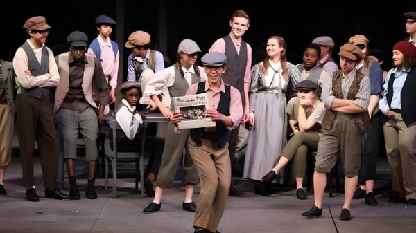 Eine Gruppe Schüler steht auf der Bühne der Sidwell Friends School und hält Requisiten und Dokumente.