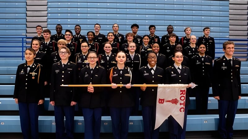 Eine Gruppe Schüler des Sierra Vista Unified School District steht mit schwarzen Uniformen vor blau-grauem Hintergrund und hält ein Banner.