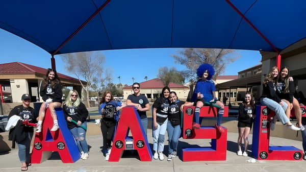 Eine Gruppe von Schülerinnen und Schülern in bunten Kostümen posiert vor großen roten Buchstaben mit der Aufschrift CASA im Sierra Vista Unified School District.