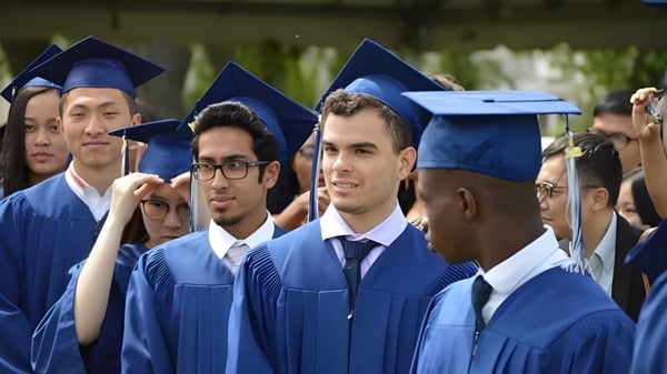 Eine Gruppe von Absolventen steht in blauen Talaren und Hüten vor Bäumen auf dem Campus des Silverthorn Collegiate Institute.