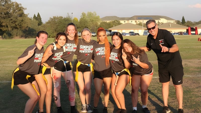 Eine Gruppe junger Sportlerinnen posiert gemeinsam auf einem Rasenfeld auf dem Campus der Simpson University.