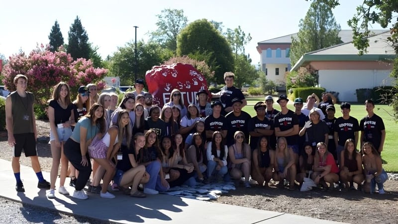 Eine große Gruppe von Schülerinnen und Schülern befindet sich im Park auf dem Campus der Simpson University.