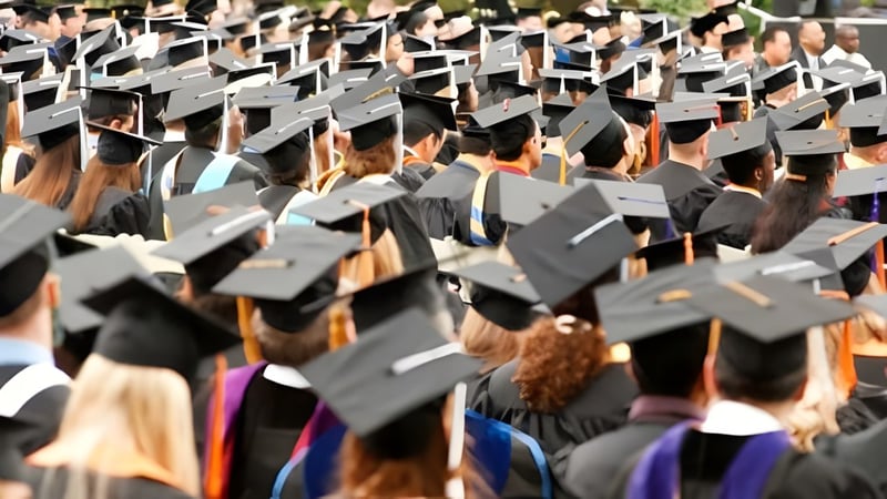 Absolventinnen und Absolventen der Sir Charles Tupper Secondary School tragen schwarze Abschlussroben und sammeln sich zur Abschlussfeier.