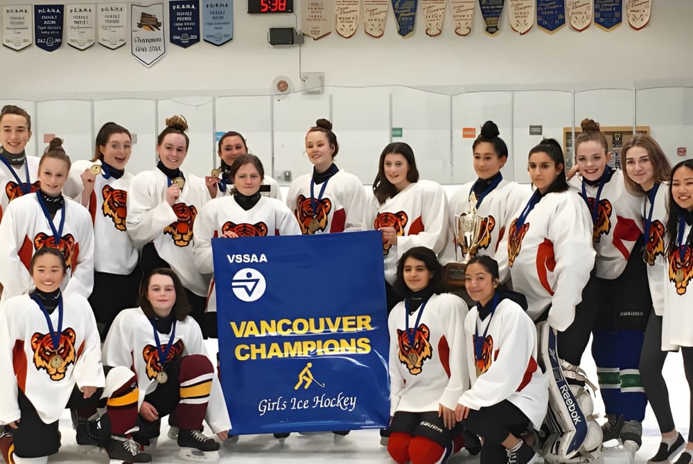 Eine Gruppe weiblicher Hockeyspielerinnen der Sir Charles Tupper Secondary School hält ein Banner mit der Aufschrift Vancouver Champions.