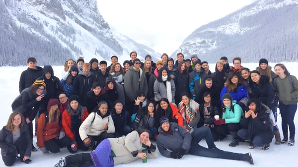 Schülerinnen und Schüler der Sir Charles Tupper Secondary School versammeln sich in einer verschneiten Berglandschaft mit schneebedeckten Gipfeln im Hintergrund.