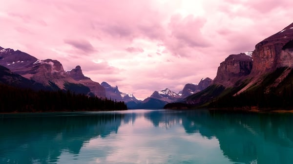 Ein ruhiger See mit türkisfarbenem Wasser vor schneebedeckten Bergen auf dem Gelände der Sir Frederick Banting Secondary School.