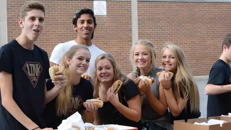 Eine Gruppe von Schülerinnen und Schülern steht gemeinsam vor einem Backsteingebäude auf dem Campus der Sir Frederick Banting Secondary School.