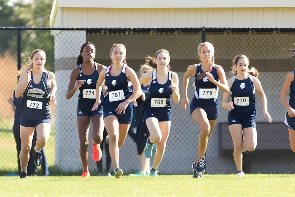 Eine Gruppe weiblicher Athletinnen läuft auf der Laufbahn auf dem Gelände der Sir Guy Carleton Secondary School.