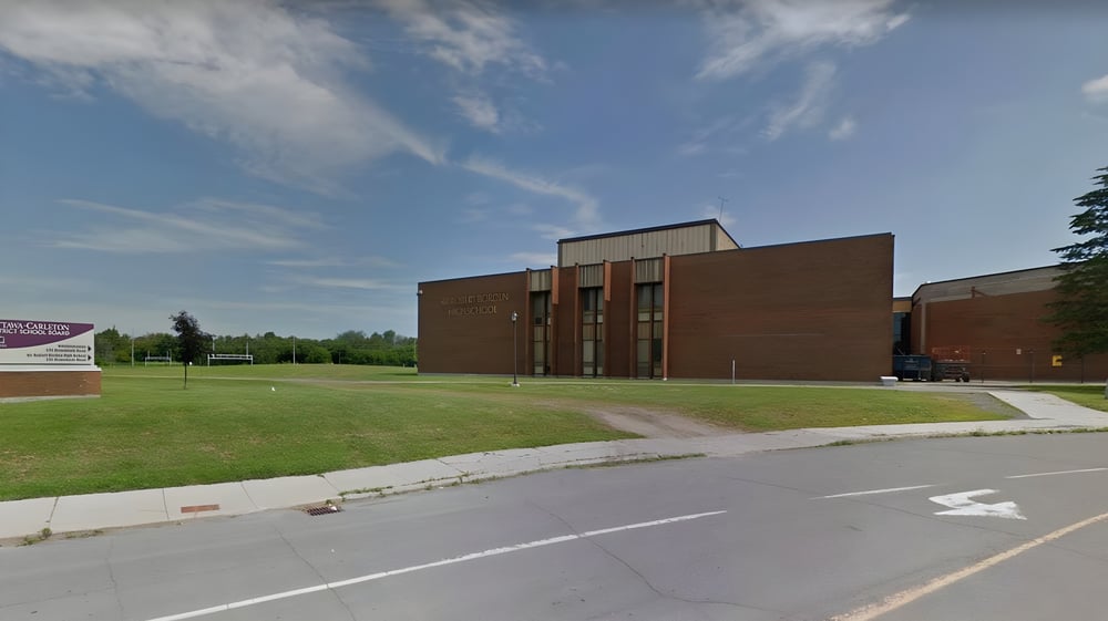 Das Backsteingebäude der Sir Robert Borden High School steht in einer grasbewachsenen Fläche unter blauem Himmel mit Wolken.