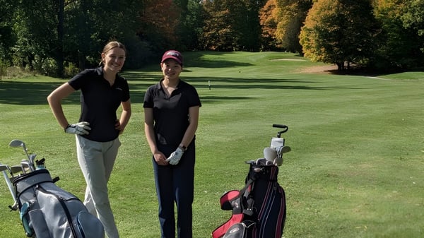 Zwei Personen in Golfkleidung stehen auf dem gepflegten Golfplatz bei der Sir Robert Borden High School im herbstlichen Umfeld.