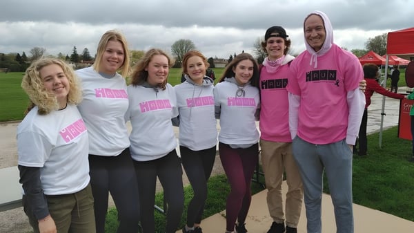 Eine Gruppe von Schülerinnen und Schülern der Sir Wilfrid Laurier Secondary School steht auf einer Wiese vor Gebäuden.