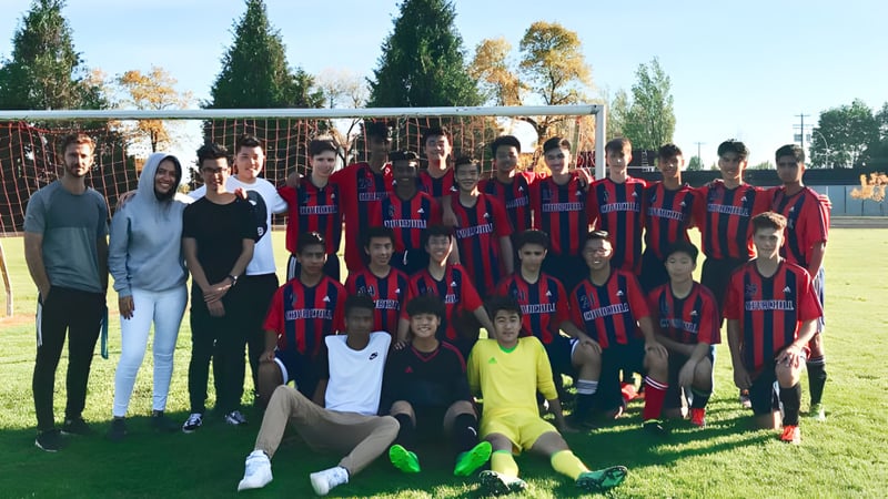 Eine Gruppe von Schülerinnen und Schülern der Sir Winston Churchill Secondary School posiert gemeinsam auf einem Sportplatz.