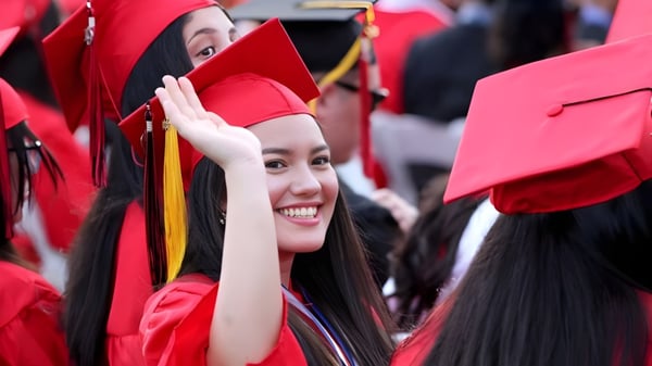 Eine Gruppe von Absolventinnen und Absolventen der Sisler High School in roten Talaren und Hüten steht zusammen.