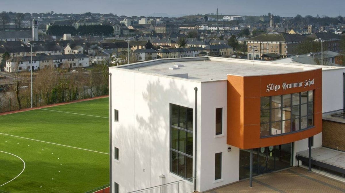 Das moderne Gebäude der Sligo Grammar School mit großen Fenstern blickt auf ein grünes Fußballfeld.