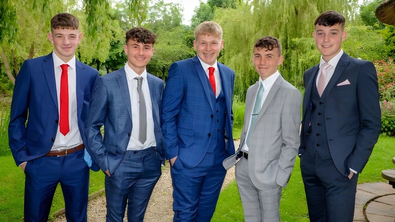 Eine Gruppe von Schülern des Slindon College steht in formellen Anzügen im grünen Außenbereich mit Weidenbäumen im Hintergrund.
