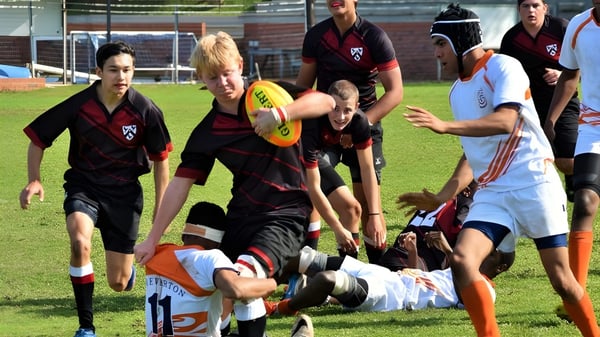 Schüler des Slindon College nehmen an einer Sportaktivität auf einem Grasfeld teil.