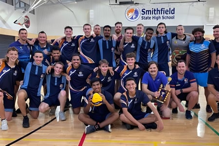 Eine Gruppe von Schülerinnen und Schülern mit Trainerinnen und Trainern posiert in der Sporthalle der Smithfield State High School.